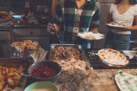 Person Picking Food on Tray - different ways to celebrate thanksgiving