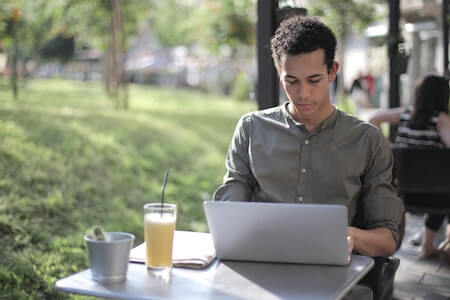 Focused freelancer using laptop in street cafe - employment reference letter
