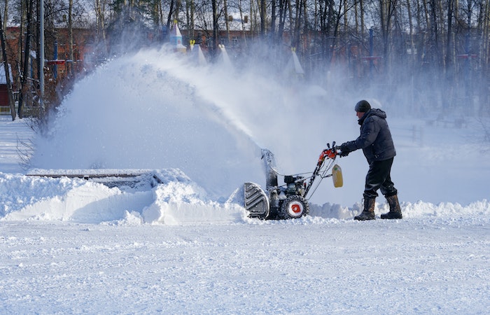 Man removing snow with snow blower - winter checklist for home
