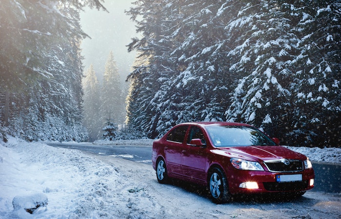Red Sedan in the Middle of Forest - rear wheel driving in snow