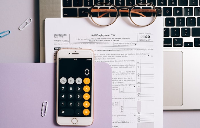 A Smartphone with a Calculator App over a Tax Document - last minute tax filing