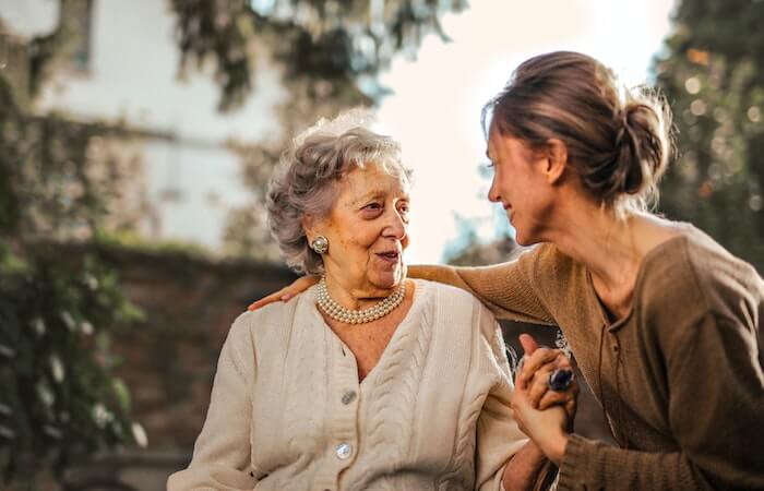 Joyful adult daughter greeting happy surprised senior mother in garden - how to make your mom feel special for mother's day